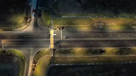 A nighttime intersection with bright street lights, traffic lights and a Stock Footage 257775077