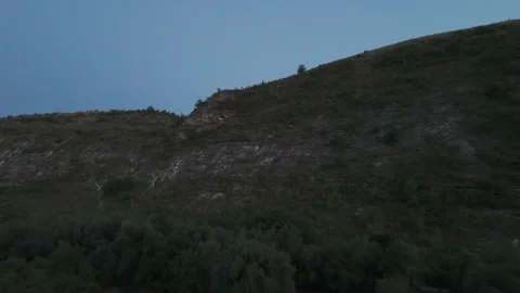 Nighttime landscape view of a hillside with trees and rocky terrain, Vídeo Stock 332725681