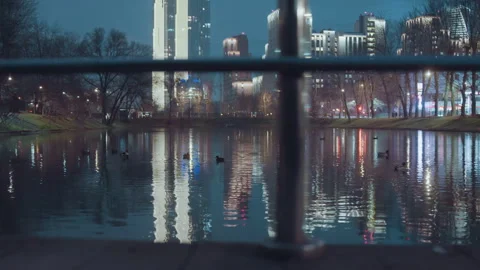 Nighttime metropolis reflected softly in peaceful water surface. Quiet city Stock Footage 345555769