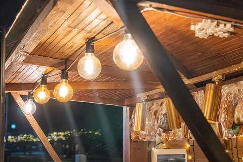 Nighttime outdoor scene featuring a rustic wooden bar structure, illuminate.. Stock Photos