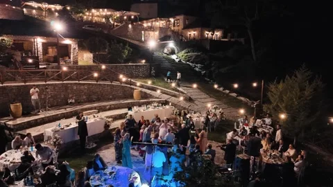 Nighttime Outdoor Wedding Reception with Guests Dancing Under String Lights Stock Footage 341883464