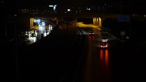A nighttime road with two lanes and an interchange separated by a streetcar line Stock Footage 223824515