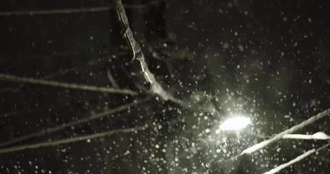 Nighttime scene capturing snowflakes falling gently under the illumination of Video stock 309885327