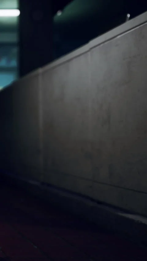 Nighttime scene in an urban area with a wall beside a walkway Stock Footage 339099074