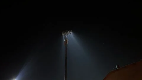 Nighttime shot features bright floodlight projecting blue-white rays into Stock Footage 320790013