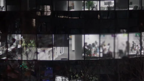 Nighttime shot of tower with workers visible through frosted glass windows Stock Footage 314928687