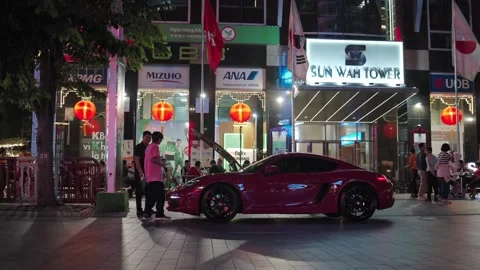 Nighttime Street Scene With Men Taking A Look At Open Hood Of Sports Car Parked Stock Footage 328586469