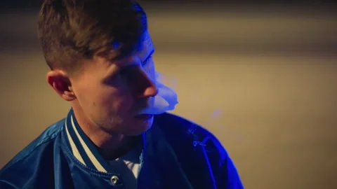 Nighttime street setting with man vaping in urban attire, Evening cityscape Stock Footage 333645793