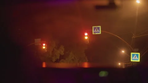 Nighttime traffic scene, Foggy intersection reveals shifting red to green lights Stock Footage 329452558