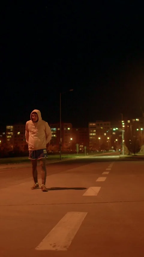 Nighttime urban dancer with expressive gestures beneath amber streetlights Vídeos de archivo 324609573