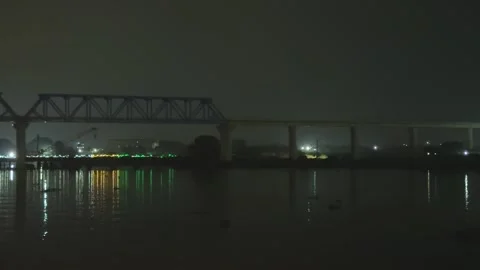 Nighttime view of a bridge with reflections on water under a dark sky and d.. Vídeos de archivo 340056067