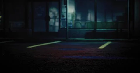 Nighttime view of an empty parking lot with faint light from nearby buildings Ilustración de archivo