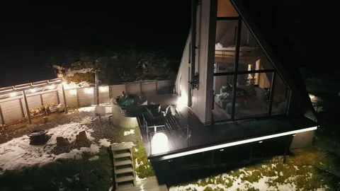 Nighttime view of modern mountain cabin with hot tub, A modern A-frame mountain Stock Footage 300602330