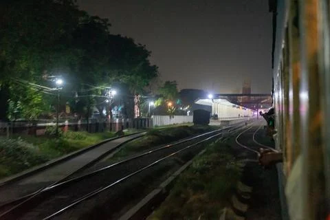 Nighttime view from a moving train, showcasing railway tracks and surrounding Stock Photos
