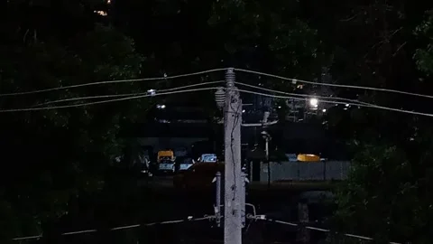 Nighttime view of utility pole power lines and streetlight traffic. Vídeos de archivo 346785832