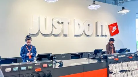 Nike store interior featuring two employees at checkout counters with Just Do It Stock Photos