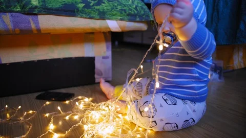 Nine-month-old chubby cute baby playing with a garland on the floor at home. Stock Footage 129893379
