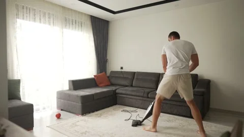 Nine year boy having fun while cleaning. A boy holds a vacuum cleaner like a Video stock 195122621