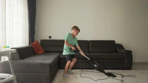 Nine year boy having fun while cleaning. A boy holds a vacuum cleaner like a Stockbeeldmateriaal 195961321