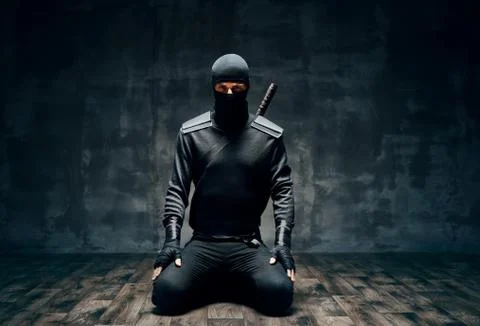 Ninja kneeling posing with a sword over black background Stock-Fotos