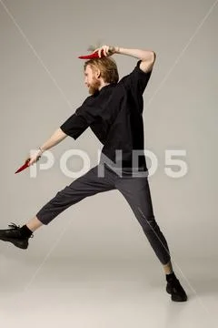 A ninja man in black wear with two red chilli peppers in his hands Stock Photos