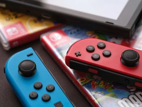 A Nintendo Switch console with detached joy-cons lying on video game boxes Stock Photos