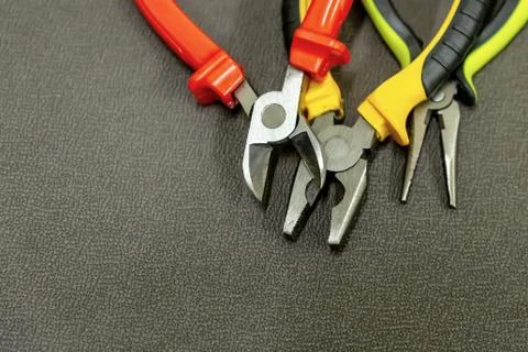 Nippers stack hand tools yellow black red handles dark gray background Stock Photos