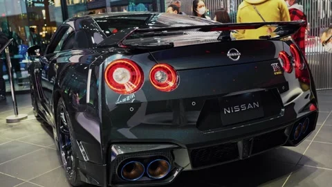 Nissan GT-R Displayed Inside Showroom as Visitors Examine Performance Car Stock Footage 337782371