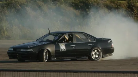 Nissan Maxima drifts around corner, tires screech and create smoke trail. Stock Footage 59747094