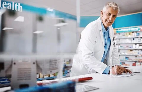 No appointment needed to get treated here. a male pharmacist writing on a Stock Photos