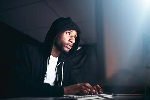 No code is uncrackable. Low angle shot of a young male hacker cracking a comp 写真素材