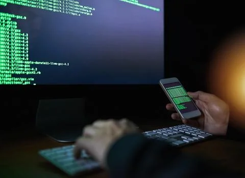 No code is uncrackable. an unidentifiable computer hacker using a smartphone to 스톡 사진