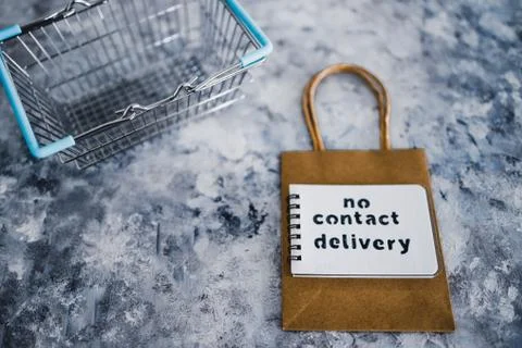 No Contact Delivery text on notepad on toop of shopping bag and next to cart  Stock Photos