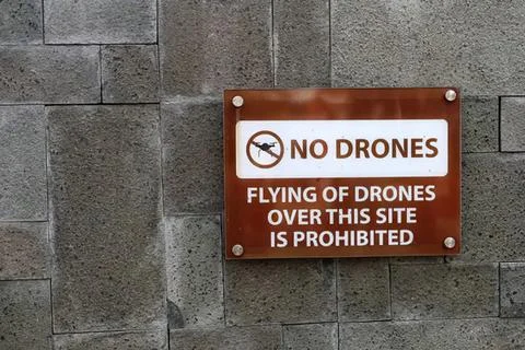 No drones sign on gray stone wall indicating drone ban Stock Photos