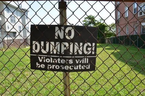 No dumping violaters will be prosecuted sign on metal fence Stock Photos