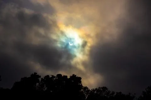 No filter Solar Eclipse with cloudy glow &amp; god rays through marine layer clouds Stock Photos