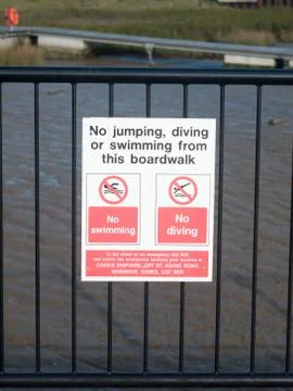No jumping, diving or swimming from this boardwalk sign on railings at dock Stock Photos