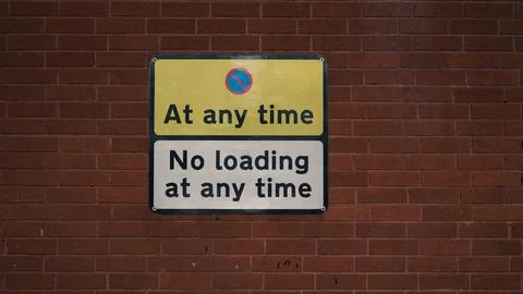 No loading sign on brick wall indicating parking restrictions at any time Stock Photos