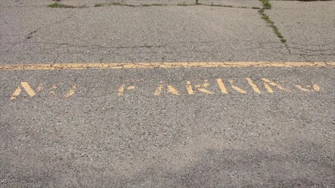 No parking caption print text writing in yellow below line on pavement, worn Stock Footage 247749123