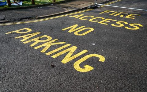 "No parking, Fire access" text sign with double yellow line on asphalt road. Stock Photos