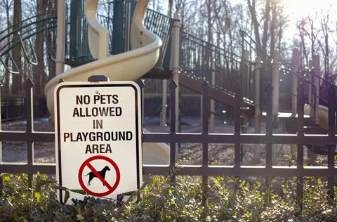 No Pets Allowed in Playground Area Sign in front of the fences at a fenced pl Stock Photos