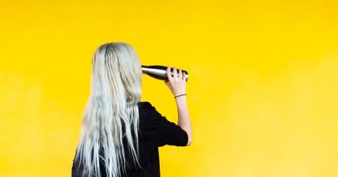 No to PLASTIC! Back view of young blonde girl with black backpack holding bottle Stock Photos