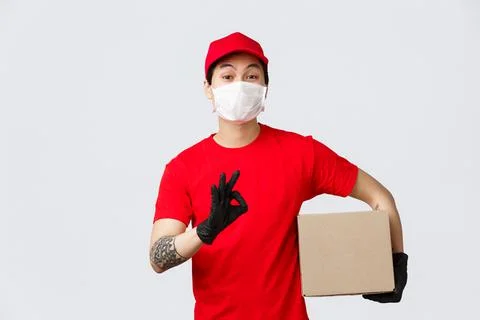No problem we deliver your parcel. Asian delivery guy in uniform, red cap and t 写真素材