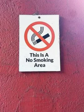 No smoking area warning board isolated on a maroon background. Stock Photos