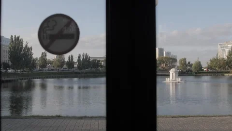 No smoking sign on a window with a view of a serene urban lake Stock Footage 253705092