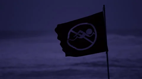 No swimming warning flag blows around at night Stock Footage 67483903