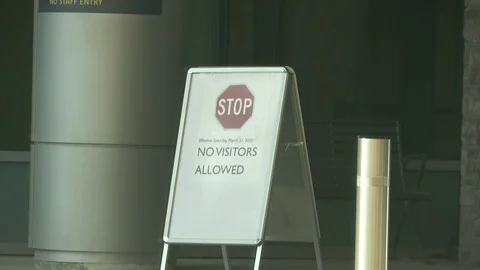 No Visitors Allowed sign in front of a hospital due to Covid-19 pandemic Stock Footage 130038228