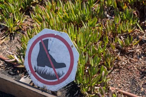 No walking boot cross out sign in front of garden with plants growing Stock Photos