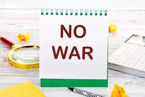 NO WAR text on the white sheet of the notebook is next to a magnifying glass, Stock Photos
