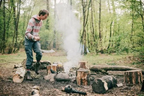Nomad creating a campfire in spring forest. Stock Photos